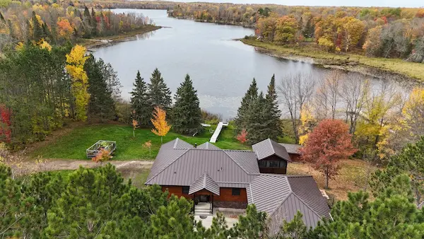 Aerial view of a finished standing seam metal roof on a wooded lakeside property in Aitkin, Minnesota