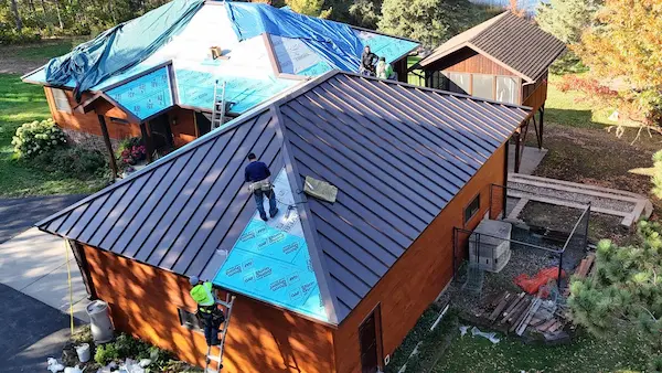 Custom metal roof installation in progress with blue roofing underlayment on a home in Aitkin, MN