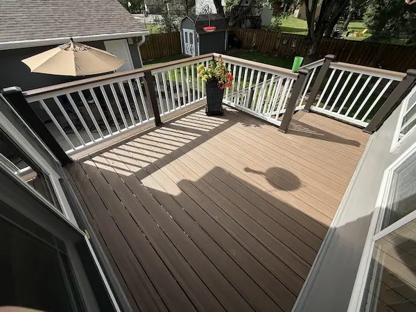 Finished TimberTech Advanced PVC deck with brown decking boards, white balusters, and dark railing posts in Champlin, MN